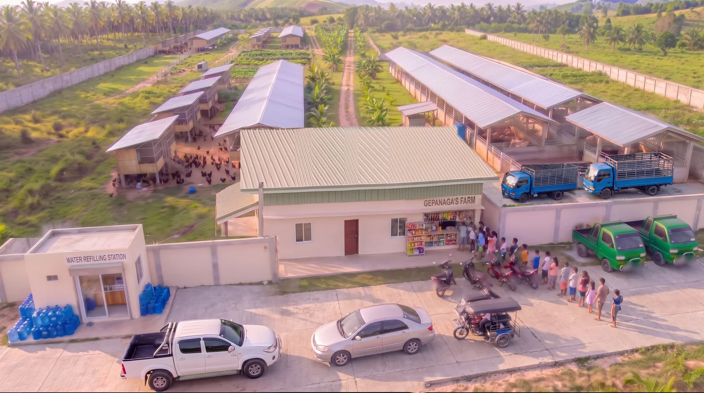 Aerial view of Gepanaga’s Farm in Ronda, Cebu: the farmhouse, parked trucks and long rows of pig and chicken houses inside a walled lot